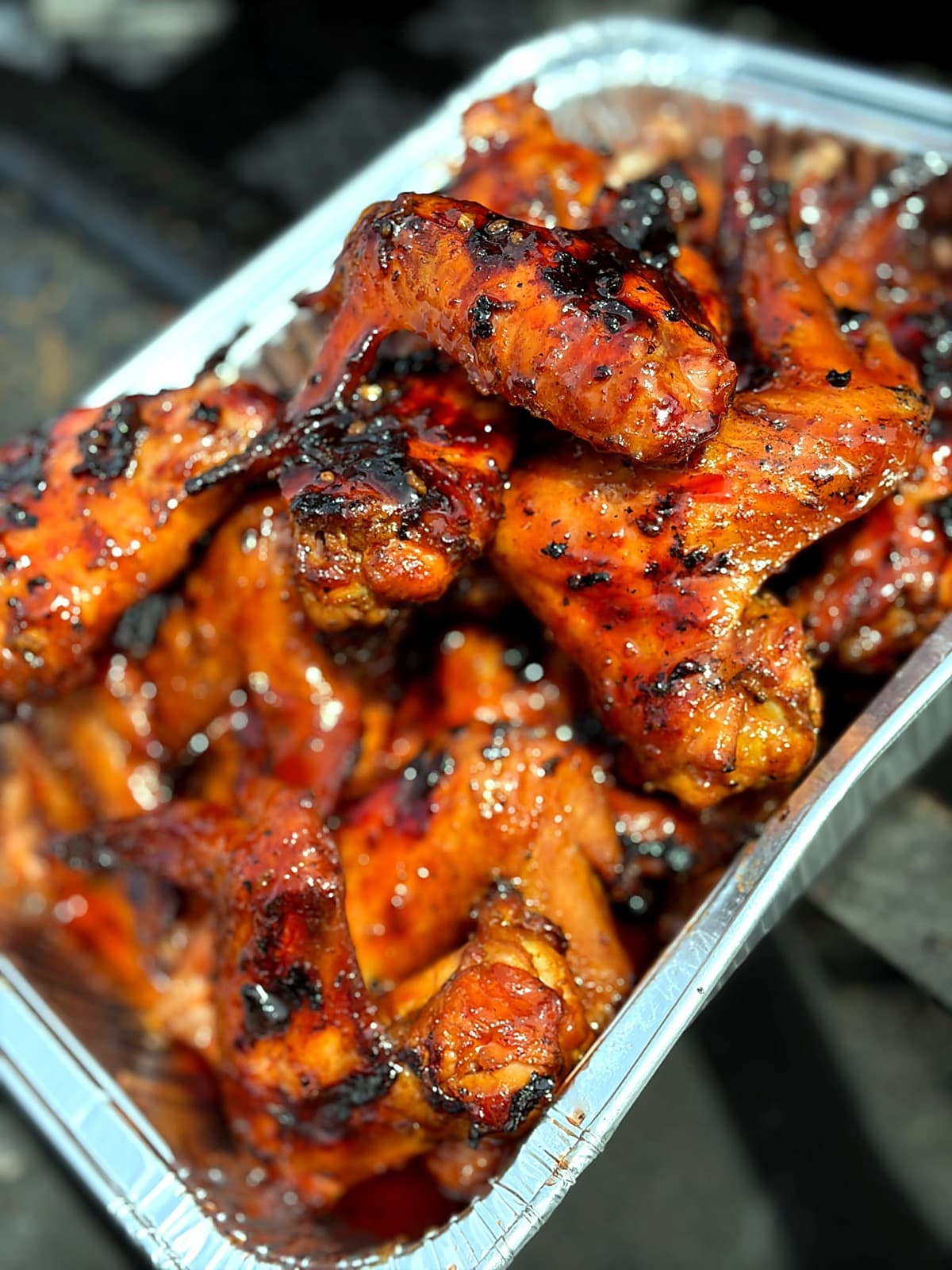 Smoked BBQ wings piled in a catering tray